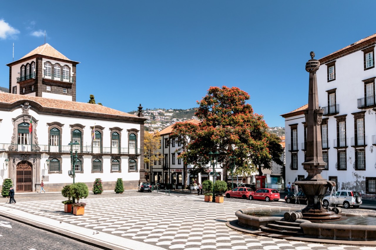 Deserted town square with old, white buildings and fountains 