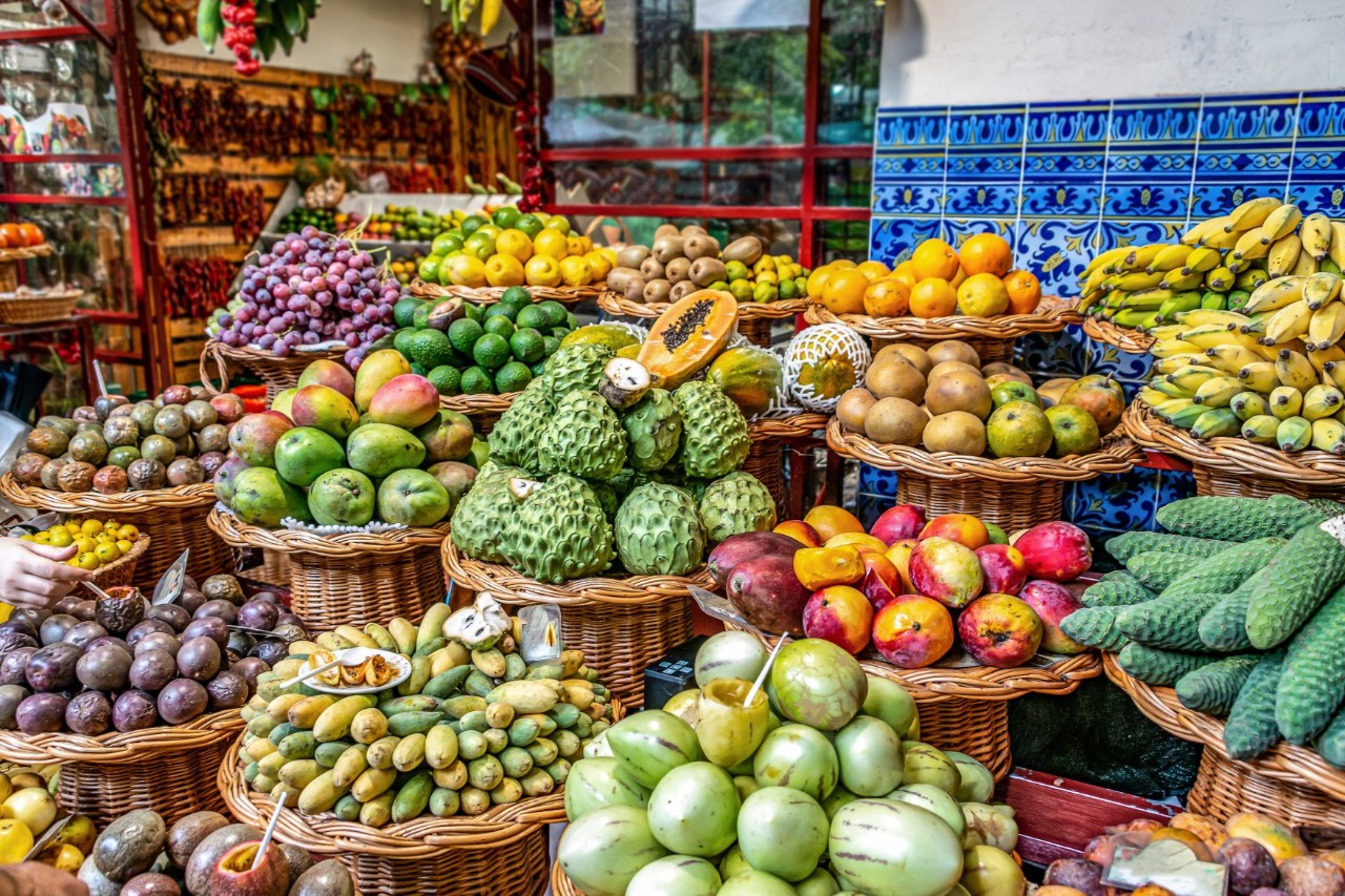 Piles of tropical fruit, such as bananas, mangoes and papayas, piled up in baskets at a market stall 