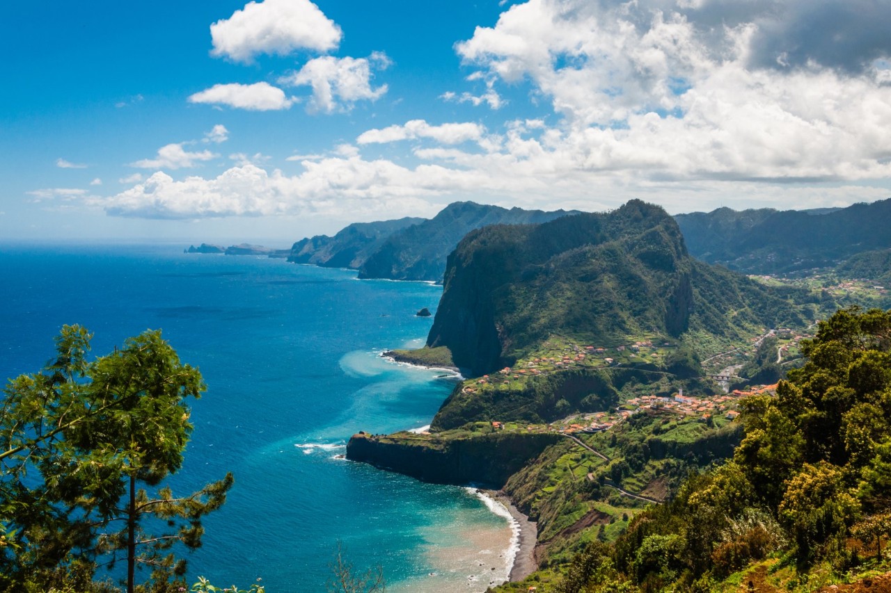 View of a coastal landscape with the sea on the left and rocks and mountains on the right 