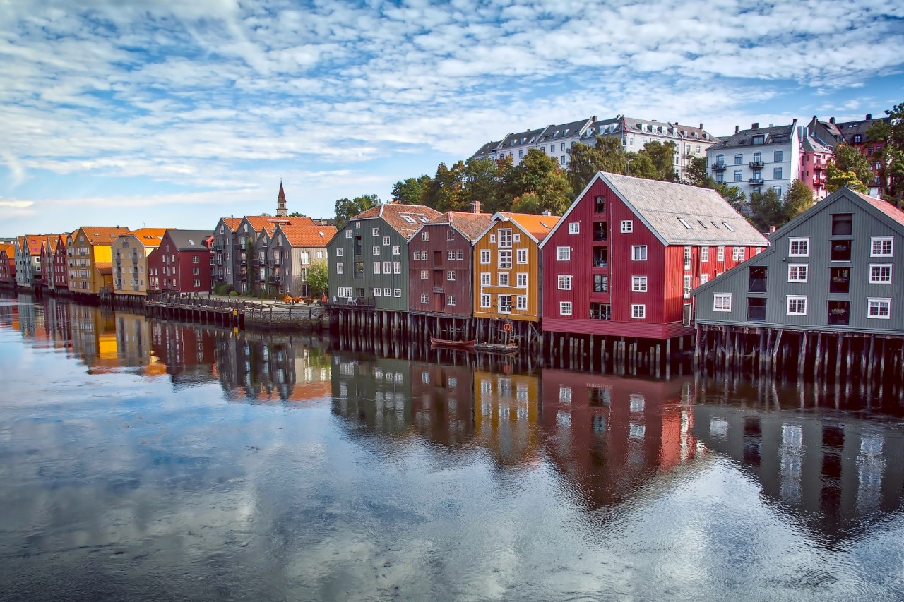 On the right of the picture, buildings with colourful fronts are reflected in a river on the left.   