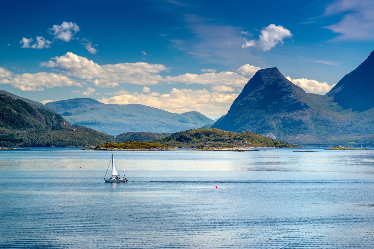 Sailing boat on the water surrounded by mountains. 