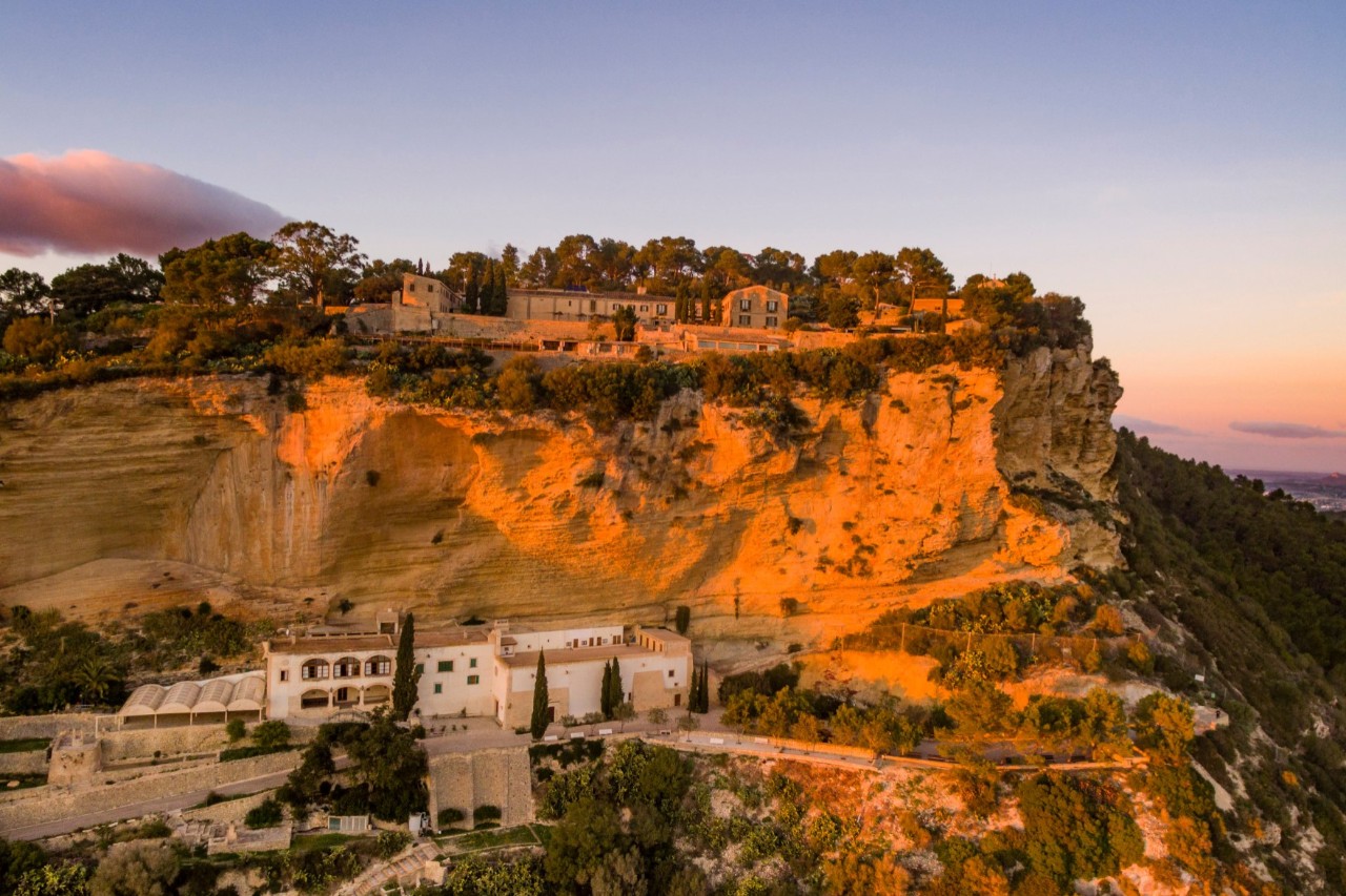 Mountain in the evening sun with several monastery buildings on the slope and ridge 