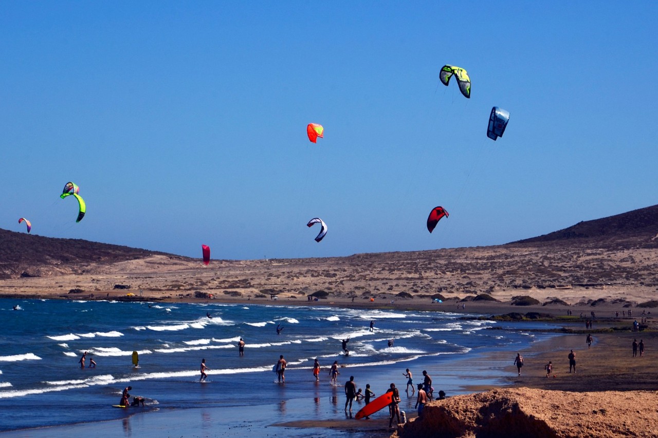 Kitesurfers, windsurfers and walkers on the beach in El Medano © svf74a/stock.adobe.com