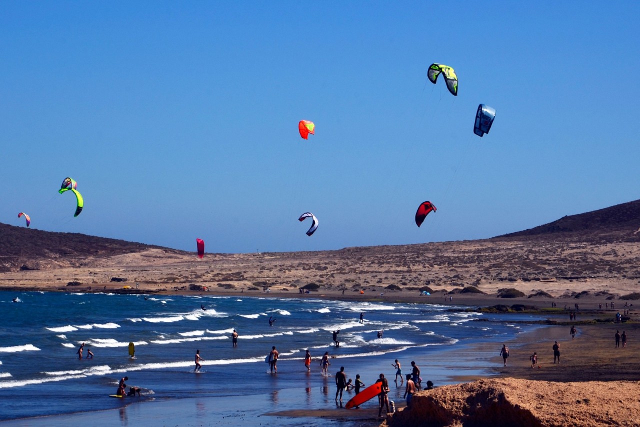 Kitesurfers, windsurfers and walkers on the beach in El Medano 
