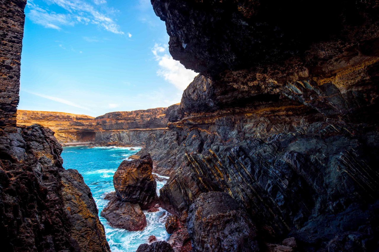 Caves of Ajuy with small bay and dark sandy beach.