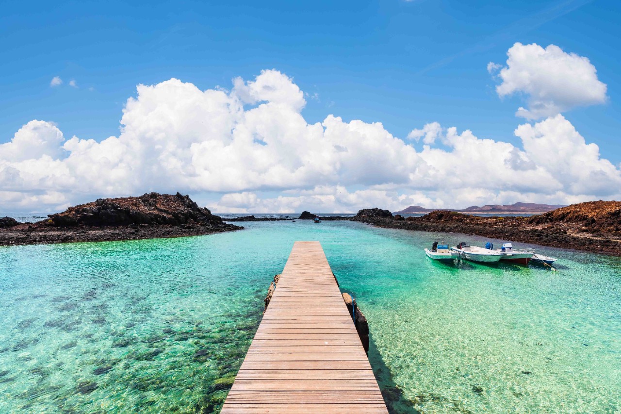 Pier with crystal-clear water on Lobos Island under sunshine.