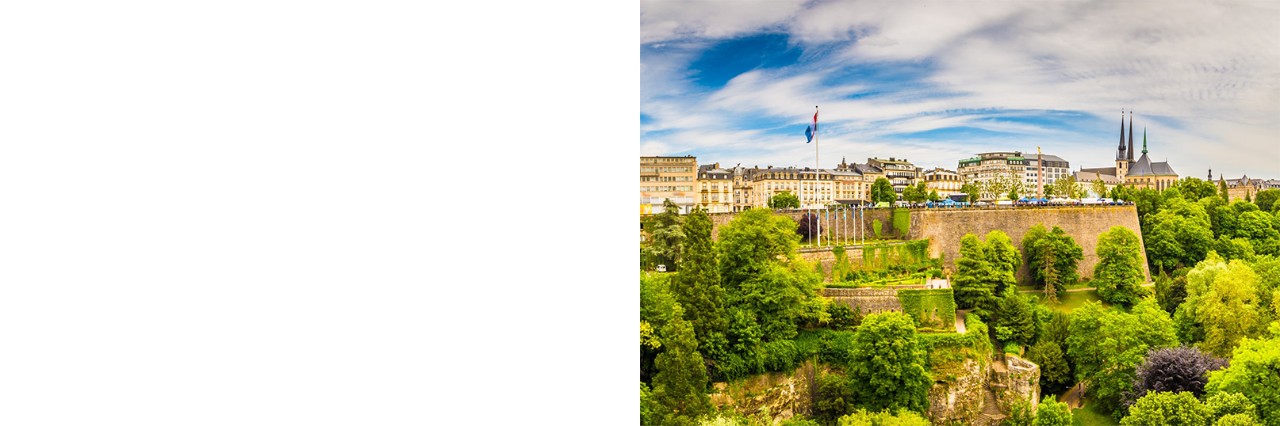 Panoramic view of Luxembourg City with fortress, buildings, church towers and lots of greenery. © powell83/stock.adobe.com