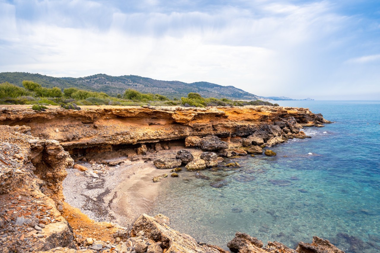 Steep cliff by the calm sea with a green, mountainous hinterland 
