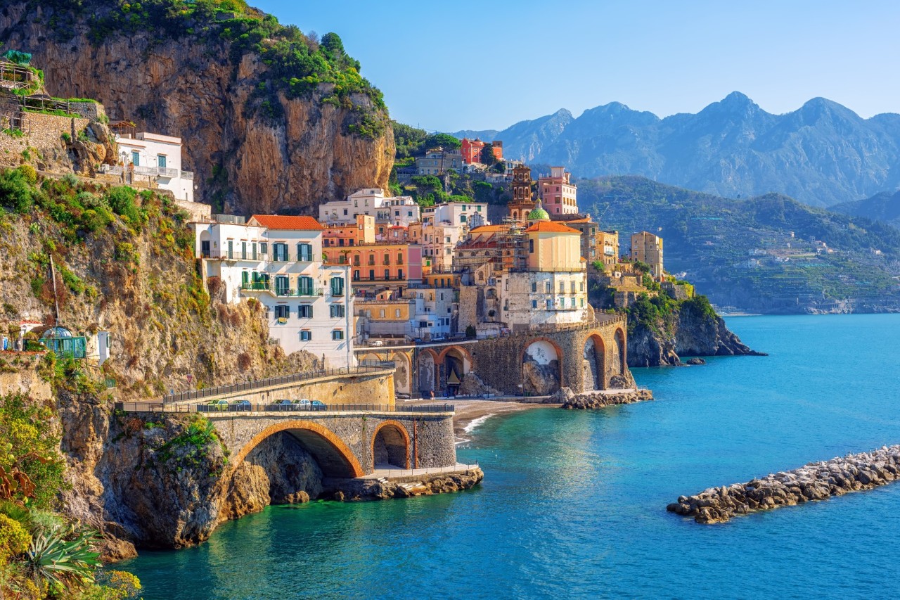 A small village situated on a cliff, along which a serpentine road leads. The road stands out thanks to arcades below that reach down to the water.