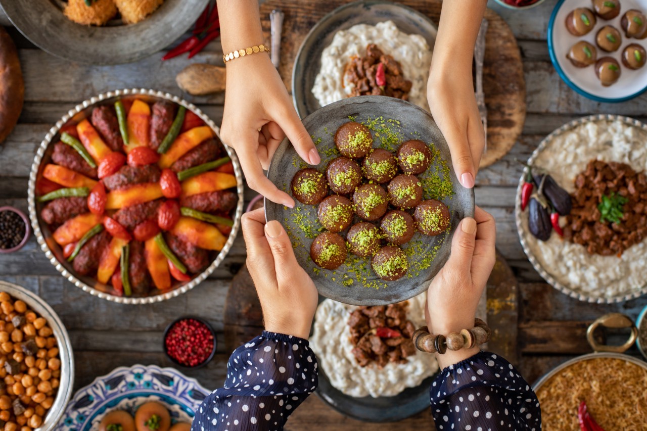 A filled plate is passed over a table set with Turkish food.