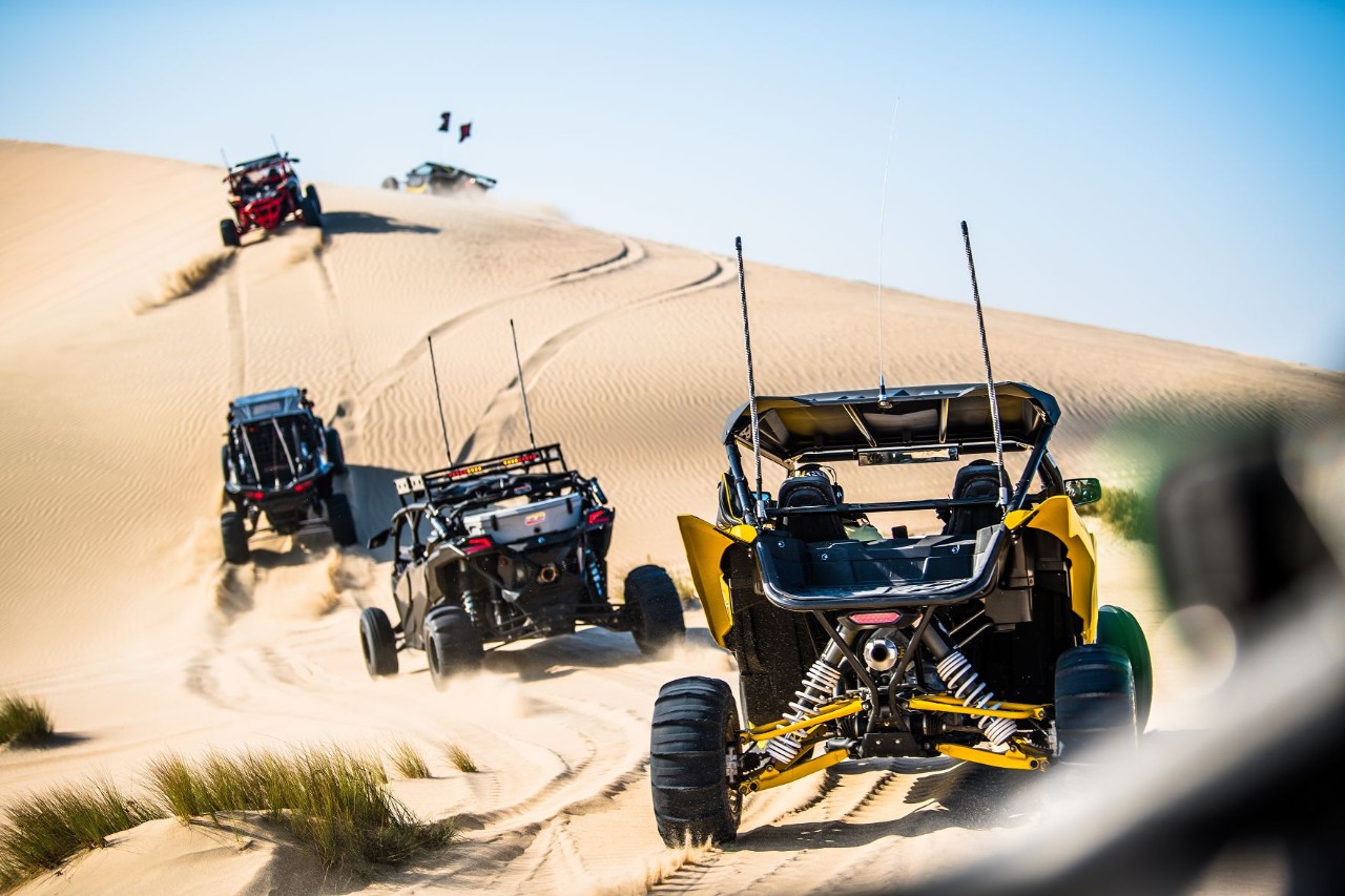 Buggies racing through the sunny desert landscape.