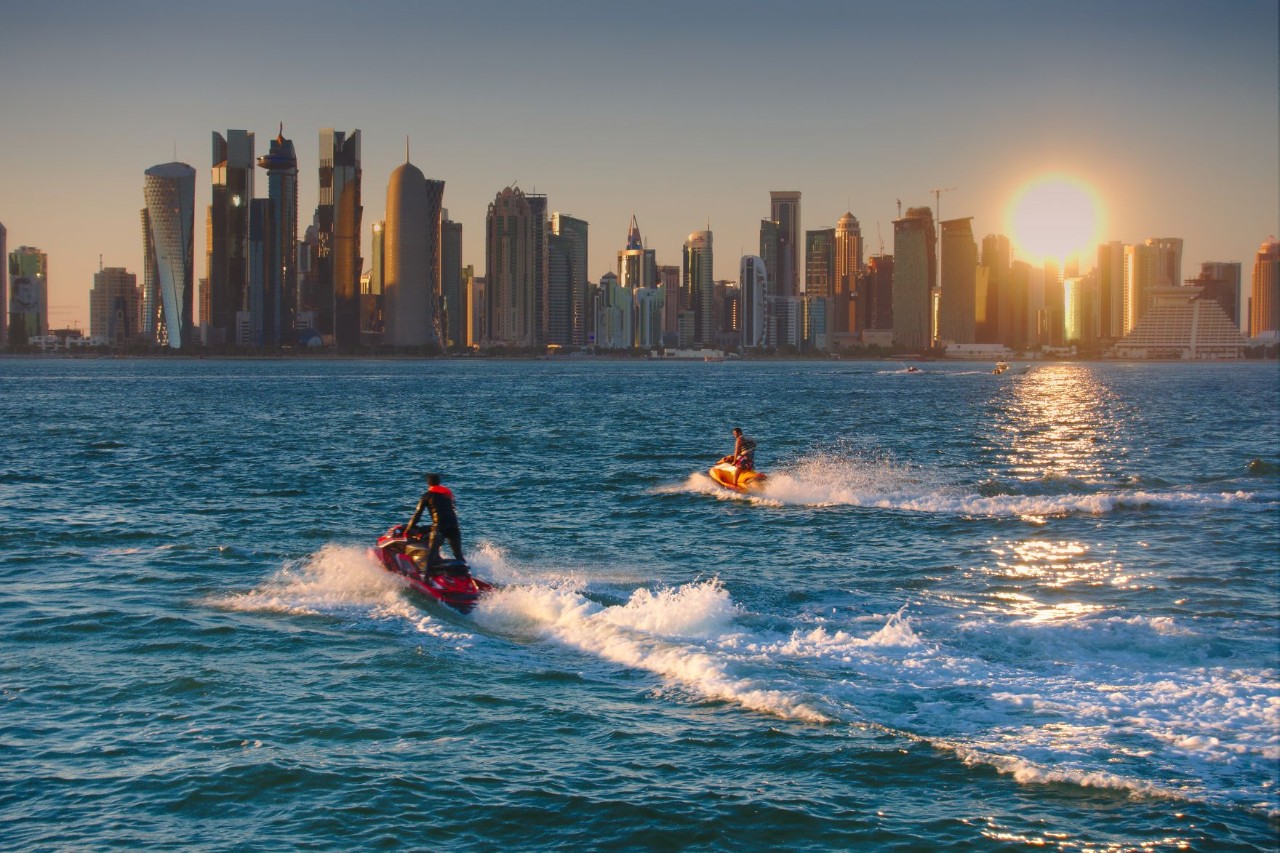 Jet skis on the sea with skyline in the background.