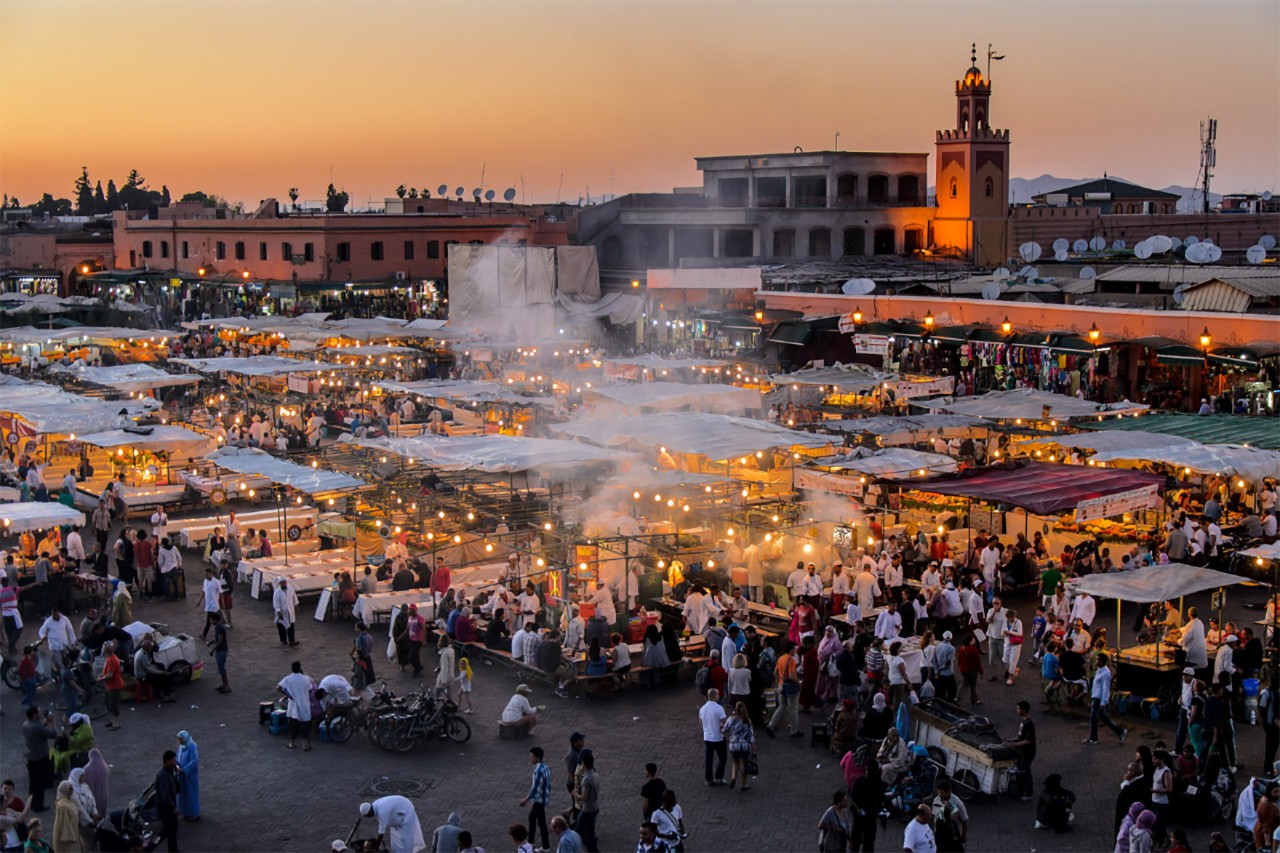 Evening market scene at Djemaa el-Fna in Marrakesh with many people.