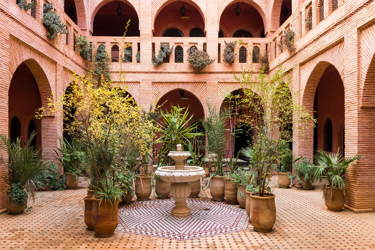 Interior of a riad with fountain and mosaic tiles in the courtyard.