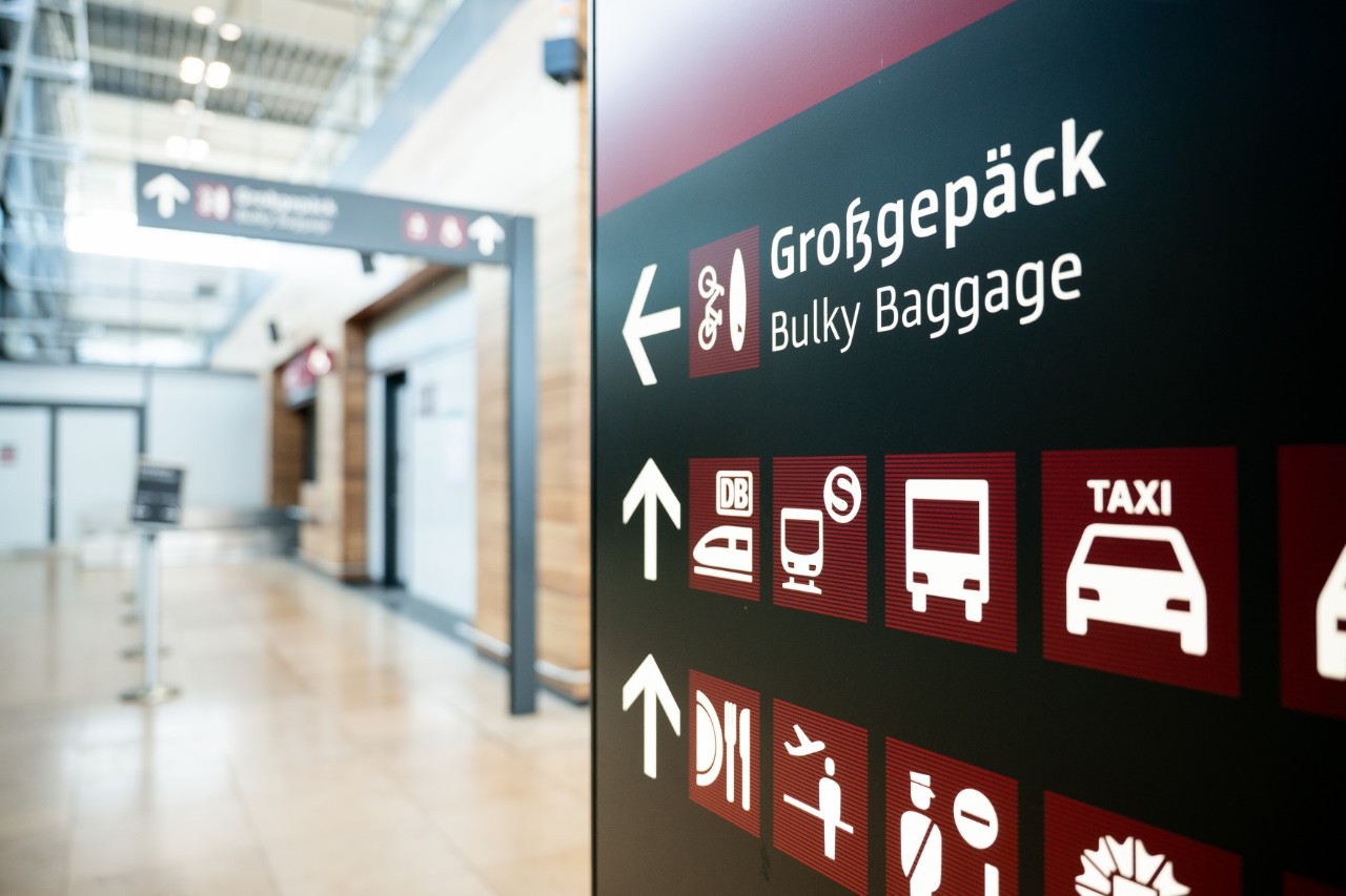 Sign pointing to the large baggage counter, which can be seen blurred in the background.