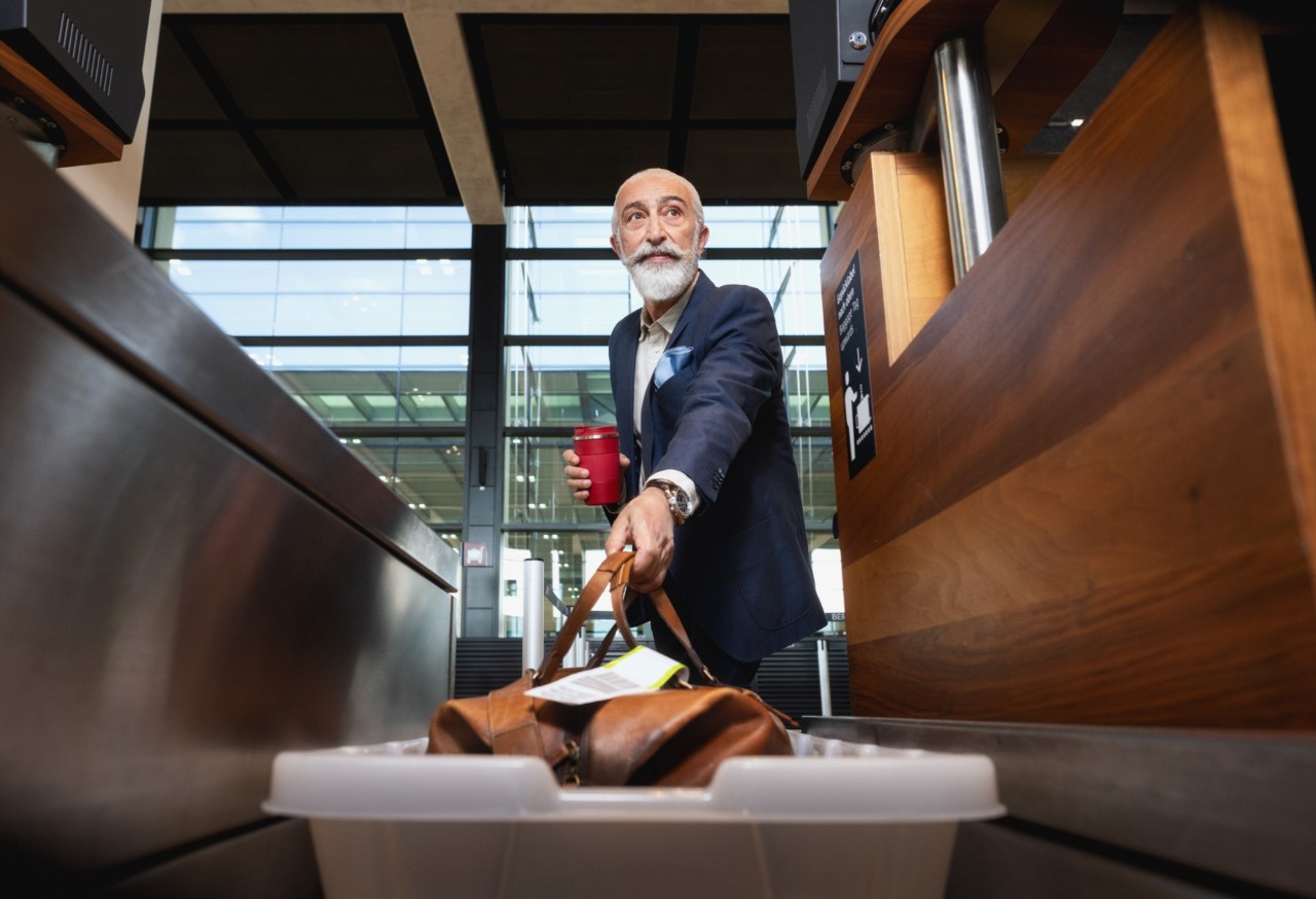 Person places a suitcase on the baggage belt.