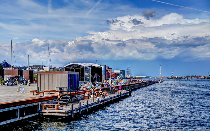 In the foreground, a harbor bath in the water. Behind it buildings.