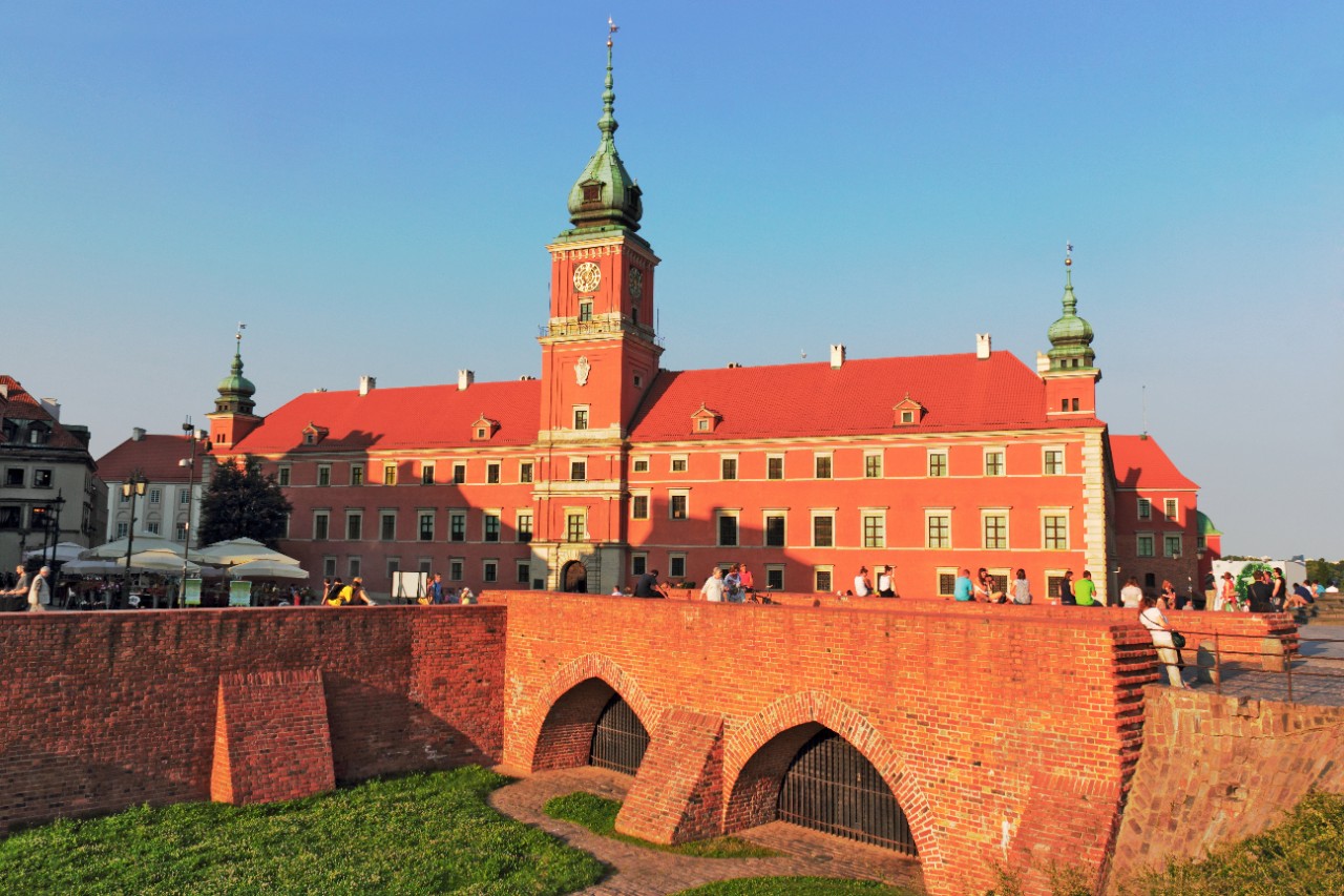 Royal Castle in Warsaw with city wall and red roof in sunshine.