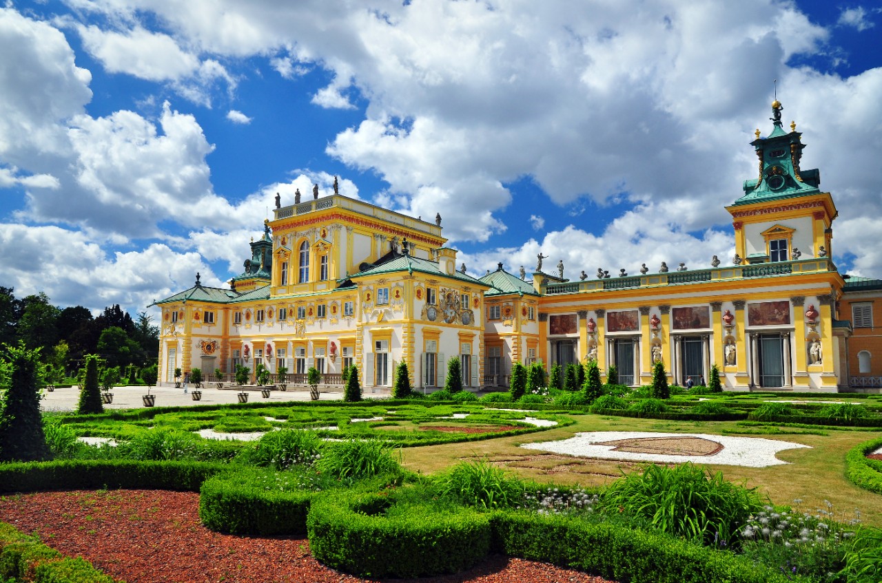 Wilanów Palace in Warsaw with yellow baroque facade and manicured garden.