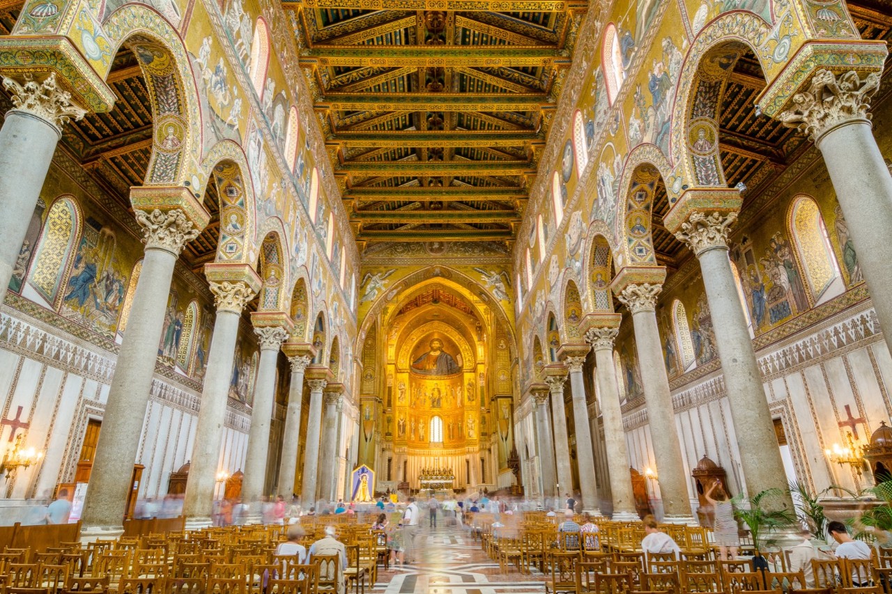 Interior of the magnificent white-gold cathedral, pillars and mosaic ceiling, seating and few visitors