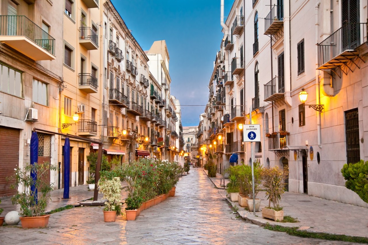 Deserted pedestrian zone in the early evening, buildings to the left and right, flowerbeds in front 
