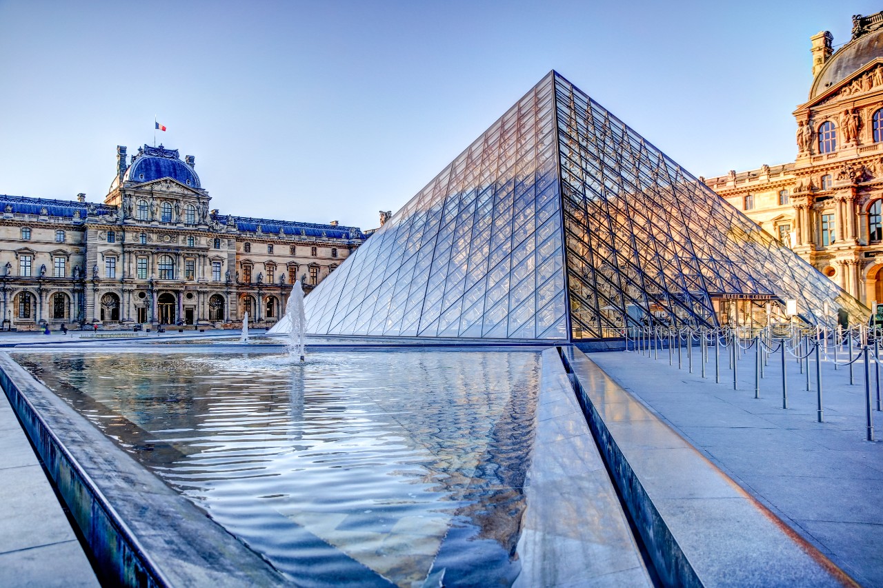 Louvre with glass pyramid in the courtyard and classical façade behind.