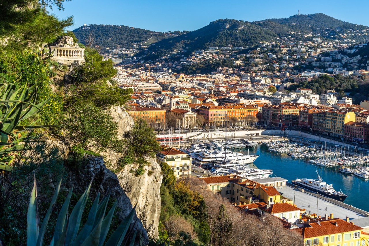 Nice’s harbour from the Colline du Château, many small boats and yachts, the city and wooded hills in the background 