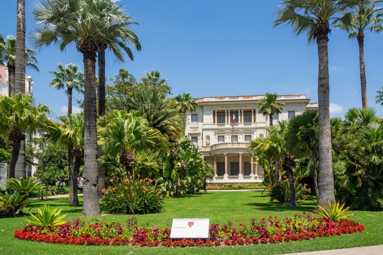 Musée Masséna with gardens, palm trees, red flowers and other shrubbery 