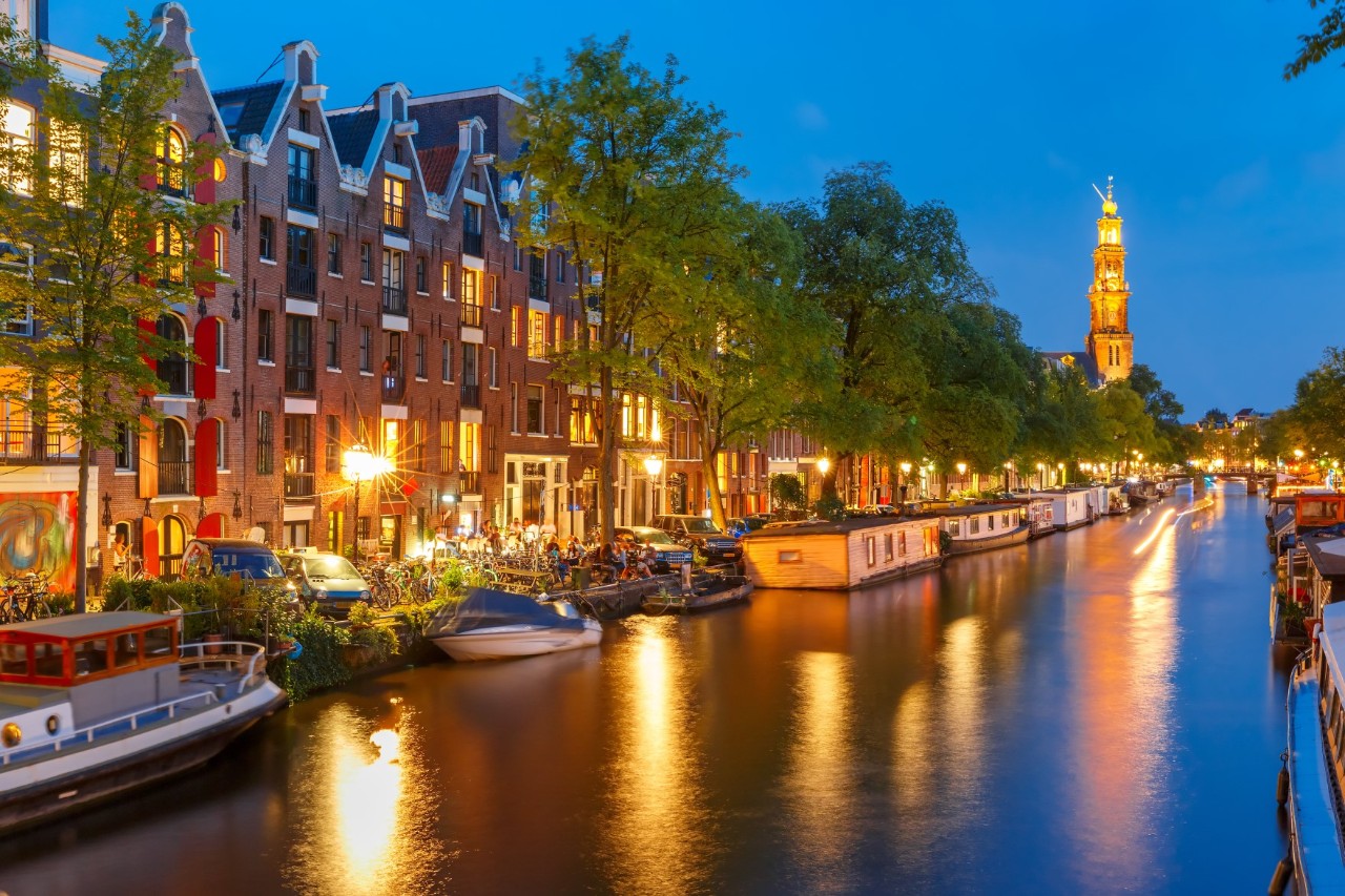 Prinsengracht at dusk with illuminated houseboats.