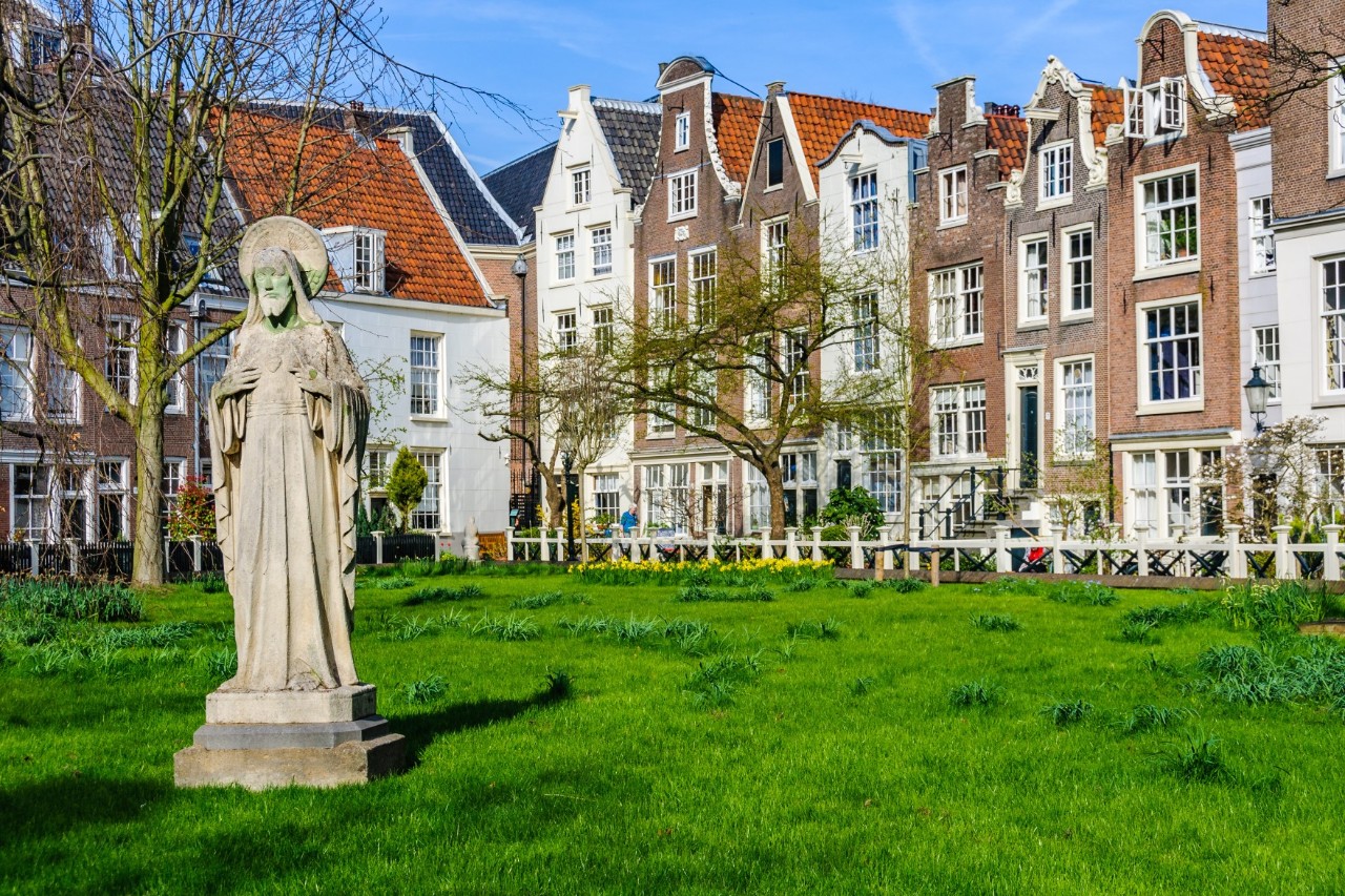 Green courtyard with old gabled houses and tiled roofs.