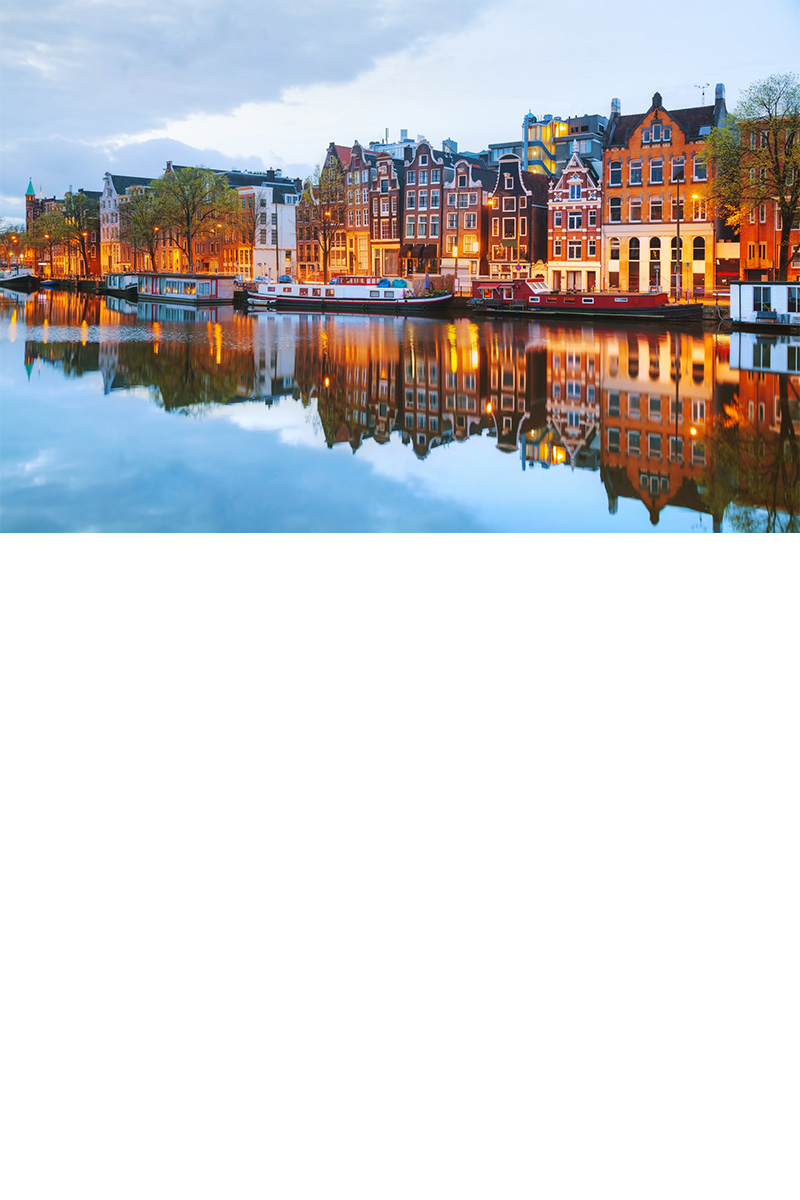 Row of houses along an Amsterdam canal with bicycles in the foreground.