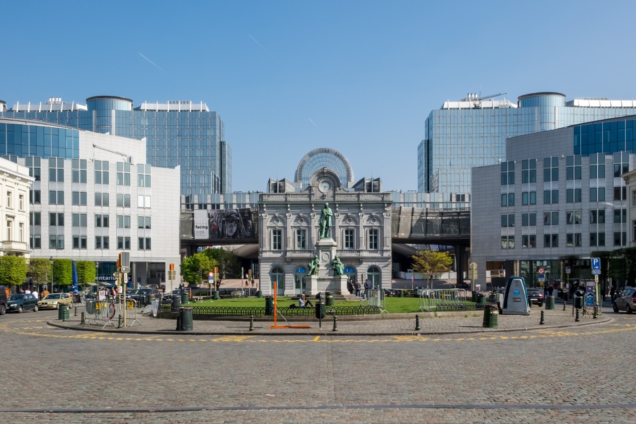 Place du Luxembourg in the European Quarter, modern buildings, European Parliament in the background, lively square with statue 