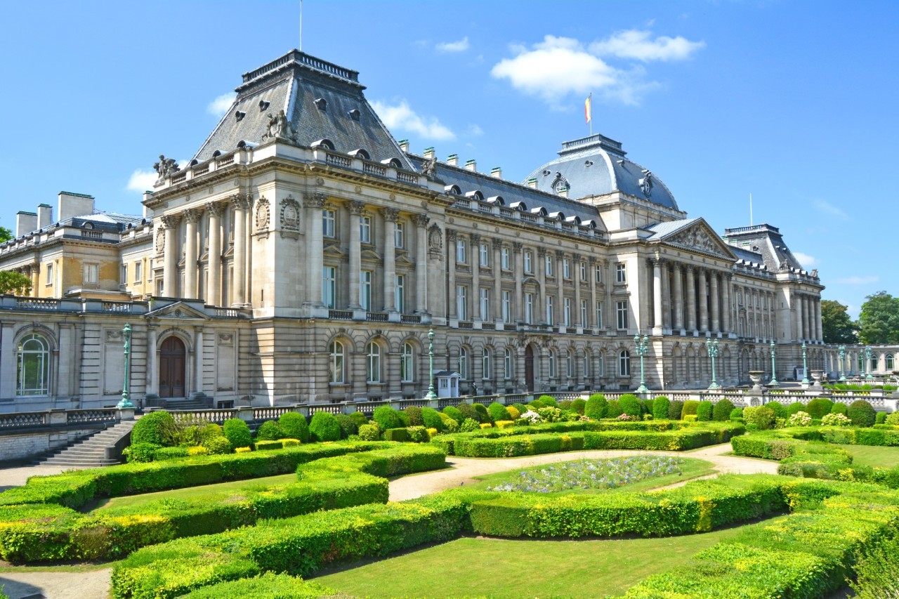 Royal palace in neo-baroque style with manicured gardens, blue sky 