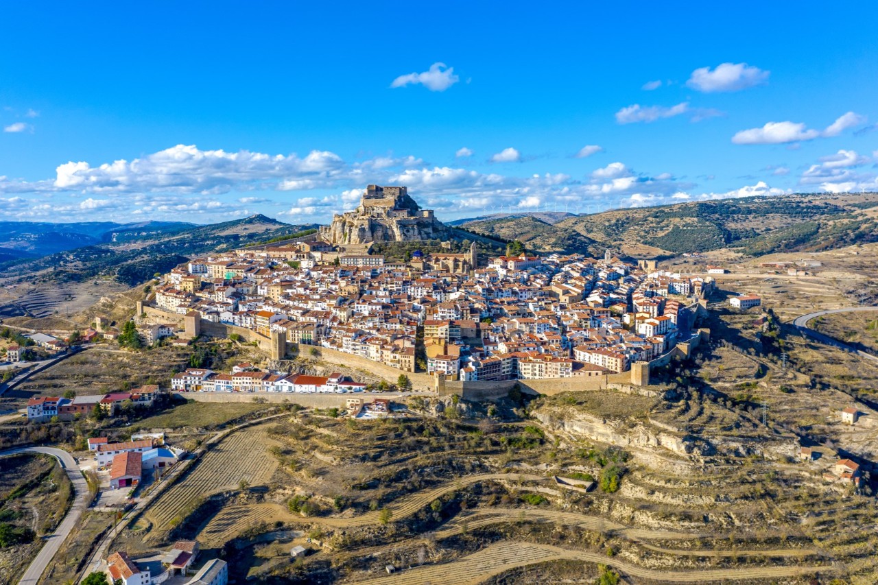The mountain village of Morella, situated in a hilly, terraced landscape 