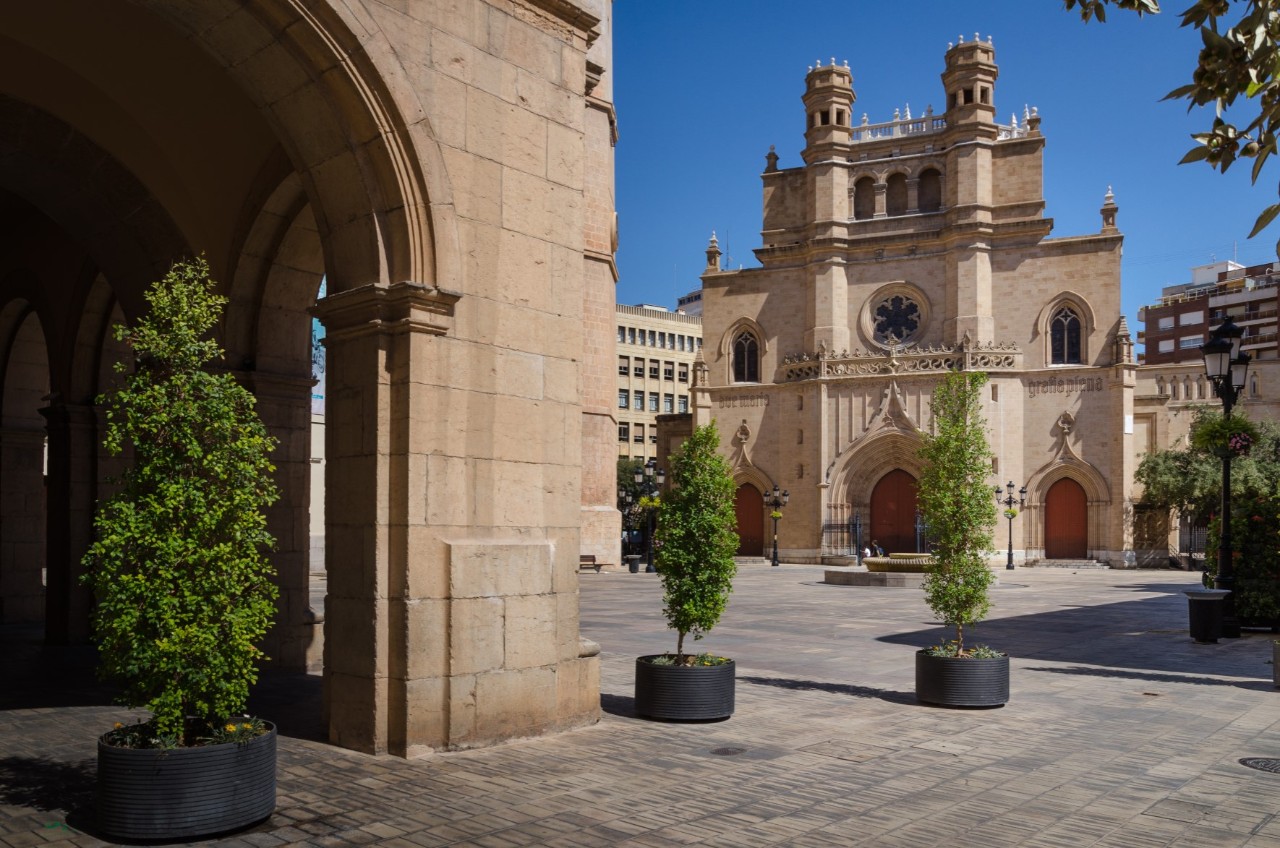 Deserted square with a cathedral. Stone archway in the foreground, other buildings in the background 