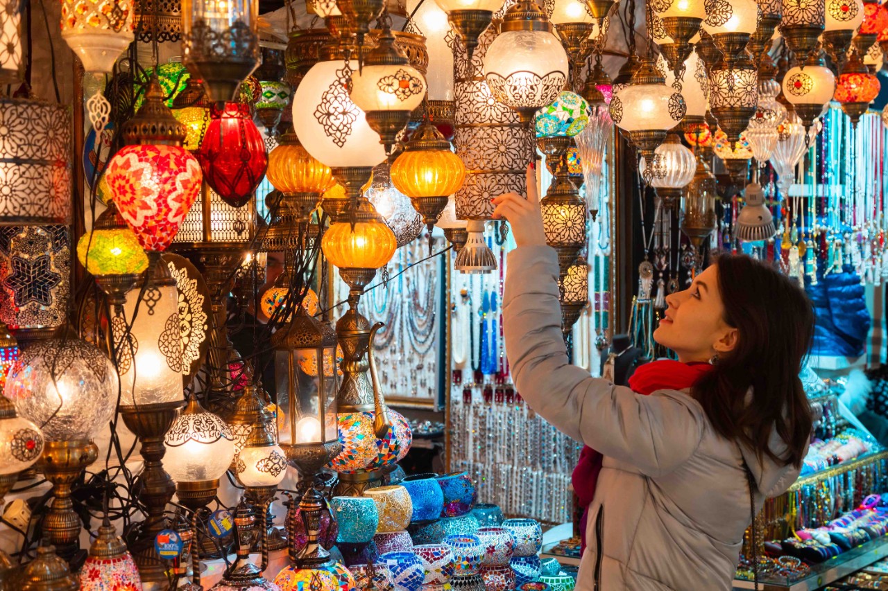 Woman standing among colorful oriental lamps in a shop.