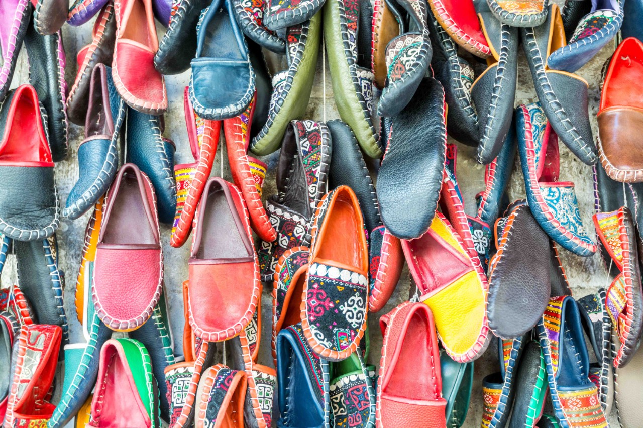 Decorated leather shoes hanging decoratively on a wall.