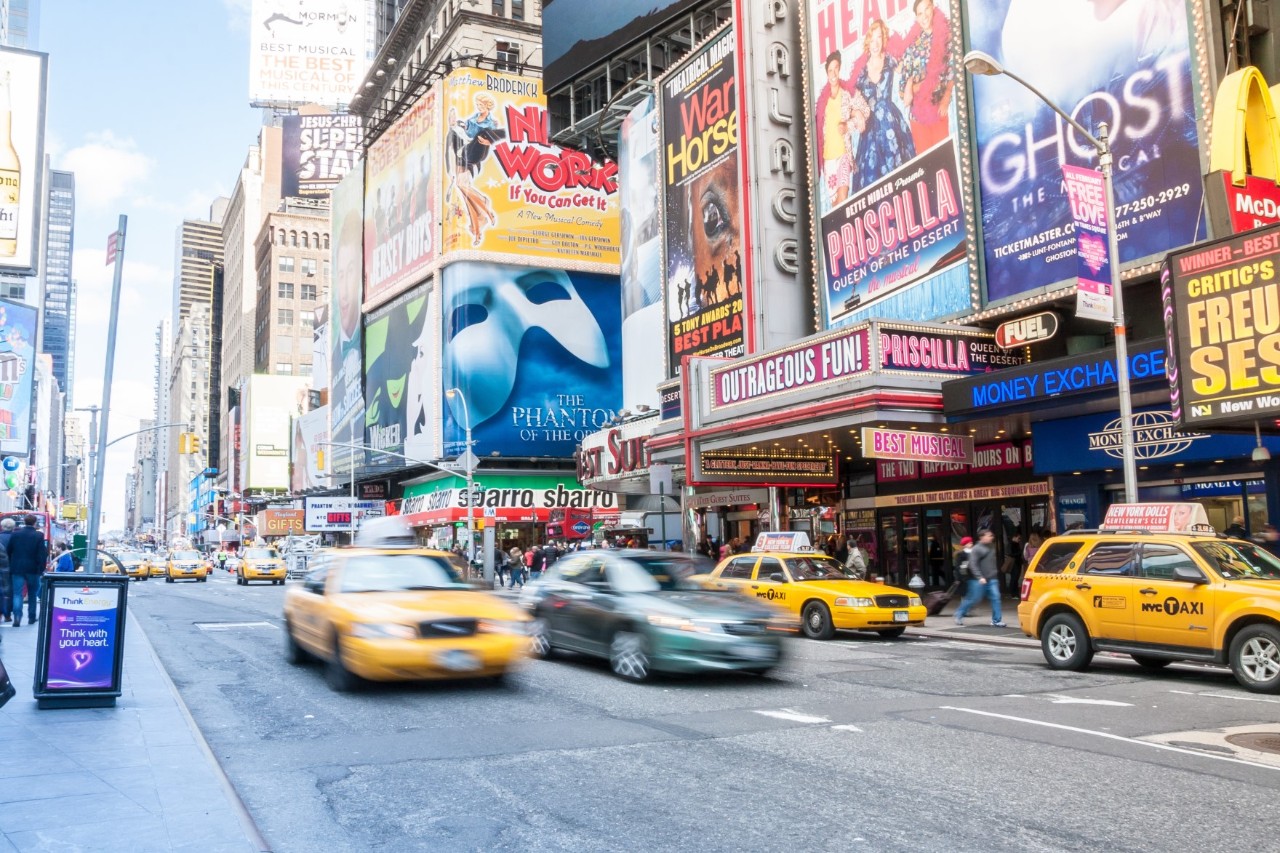 Broadway theatre. A wide street in front with yellow taxis.