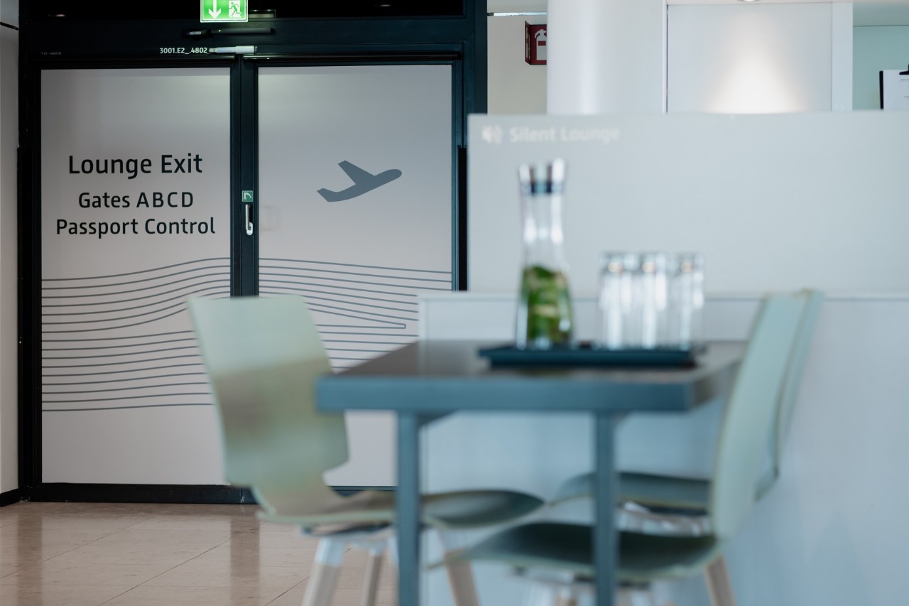 View of the entrance area. In the foreground a table with 2 chairs, behind it a door with frosted glass. ©Ekaterina Zershchikova / Flughafen Berlin Brandenburg GmbH