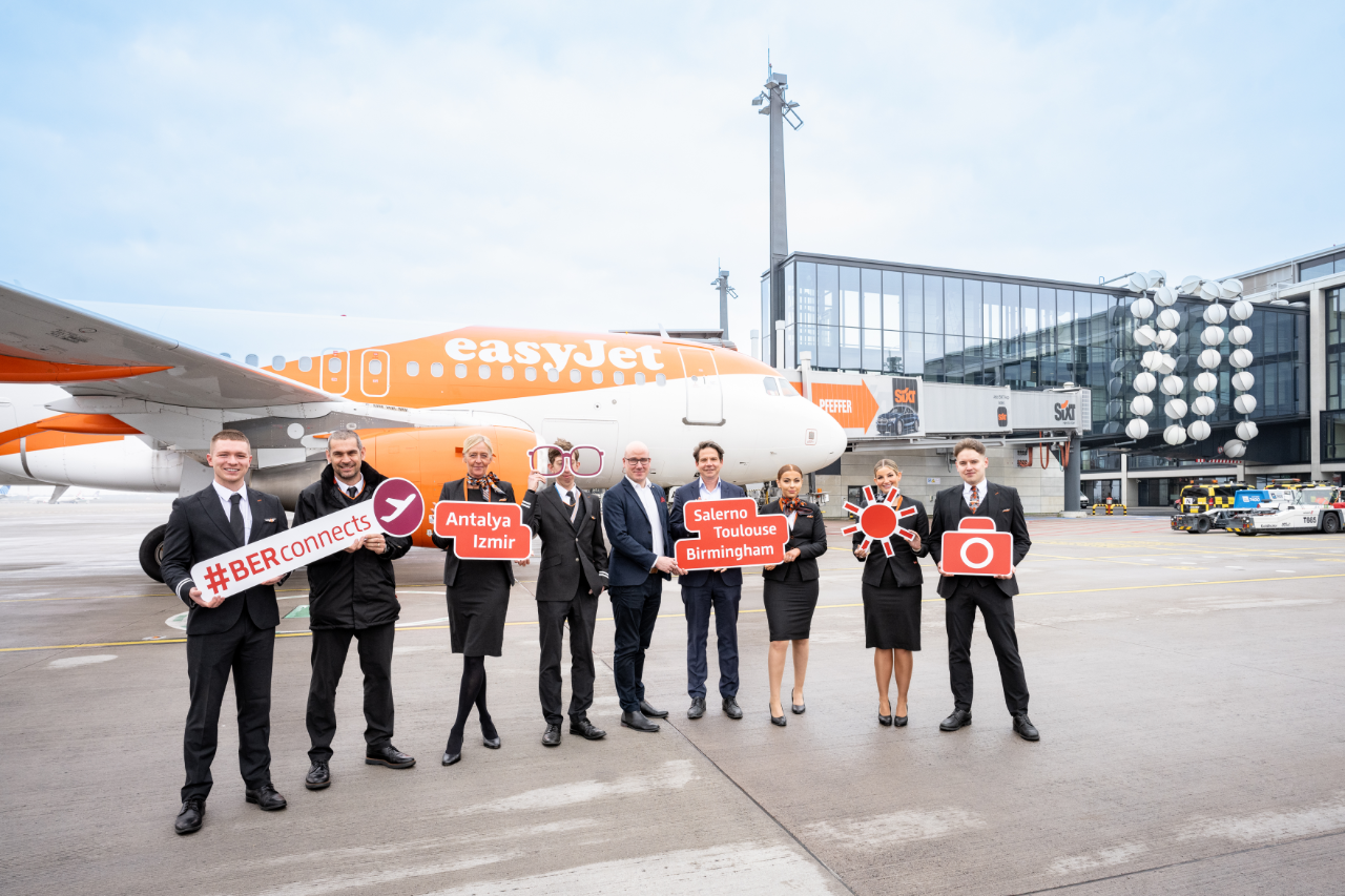 9 people with signs stand in front of an Easyjet aircraft