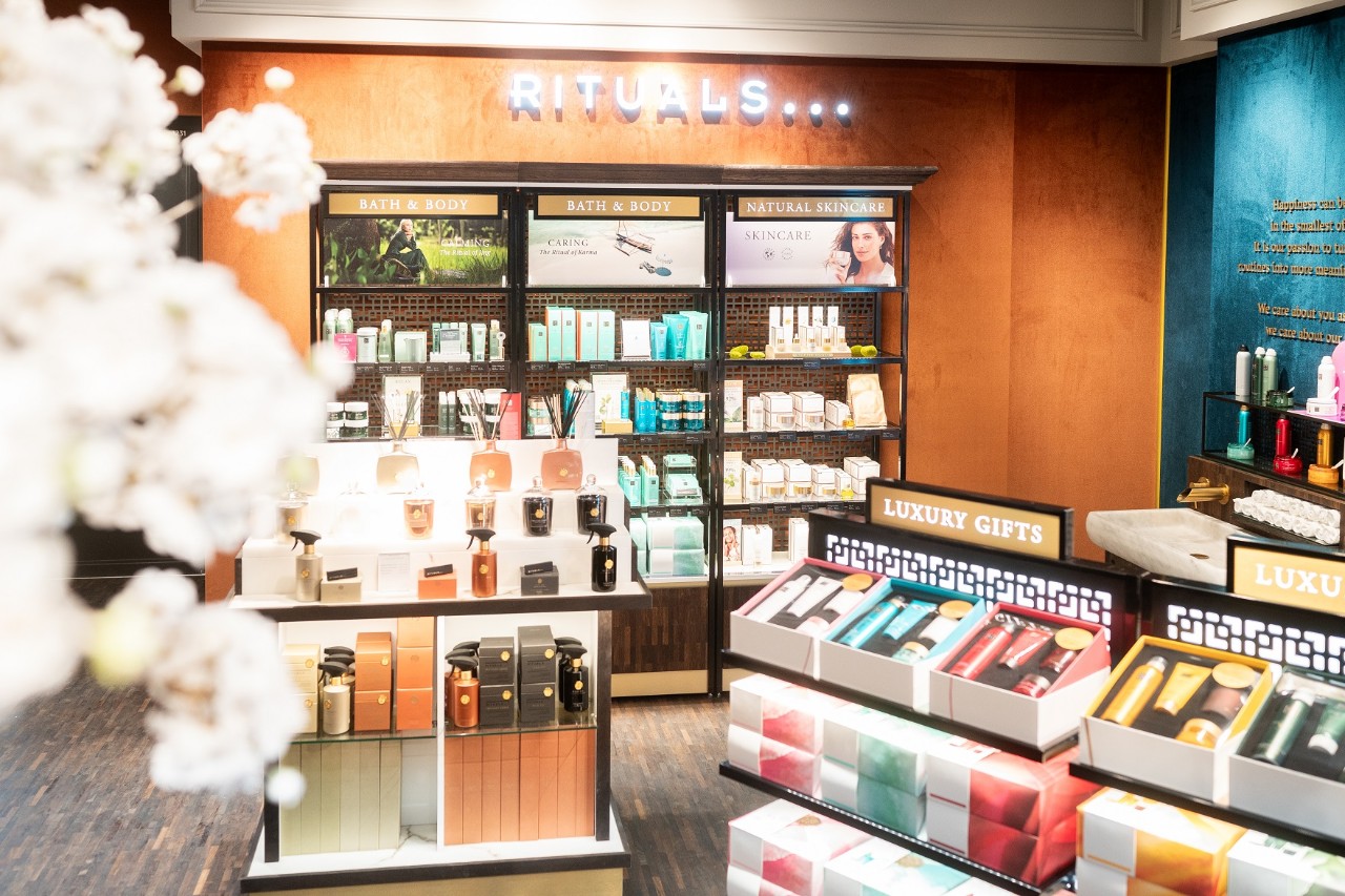 View of a wall labeled "Rituals". In front of it, shelves with fragrances and other packaging.