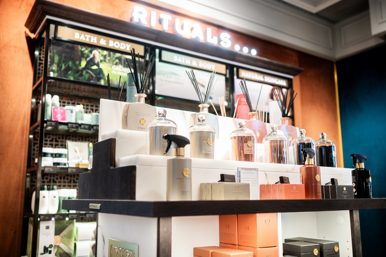 Wall with the inscription "Rituals". In front of it, packaging and bottles of perfume.