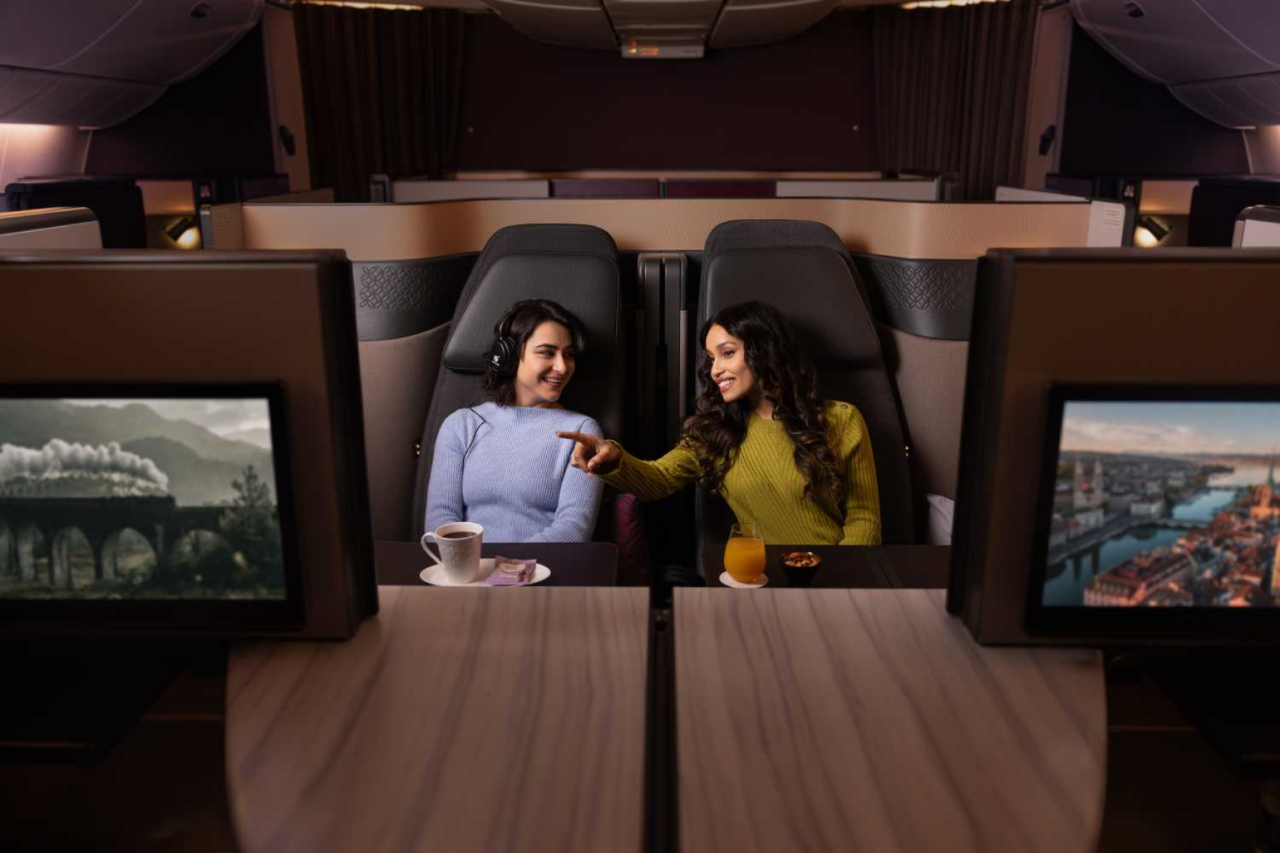 Two women in armchairs in the interior of an aeroplane. Everything is in bridal colours.