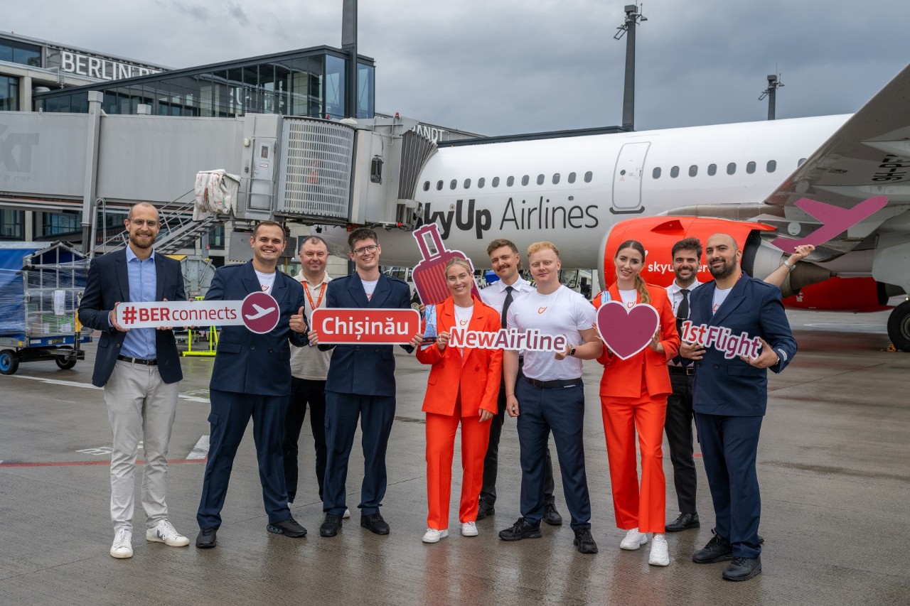 A group of people are standing in front of an aeroplane holding signs in their hands.