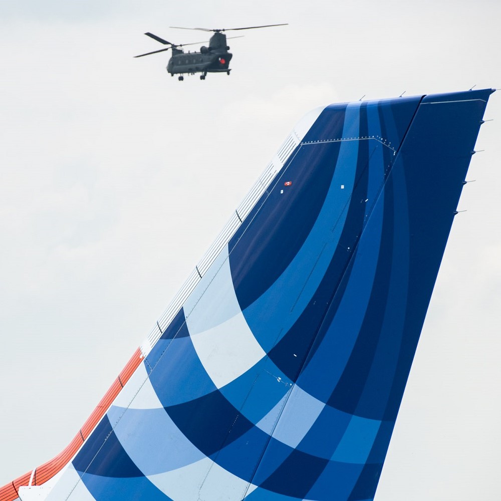 Helikopter im Hintergrund in der Luft, Flugzeug-Tail im Vordergrund.