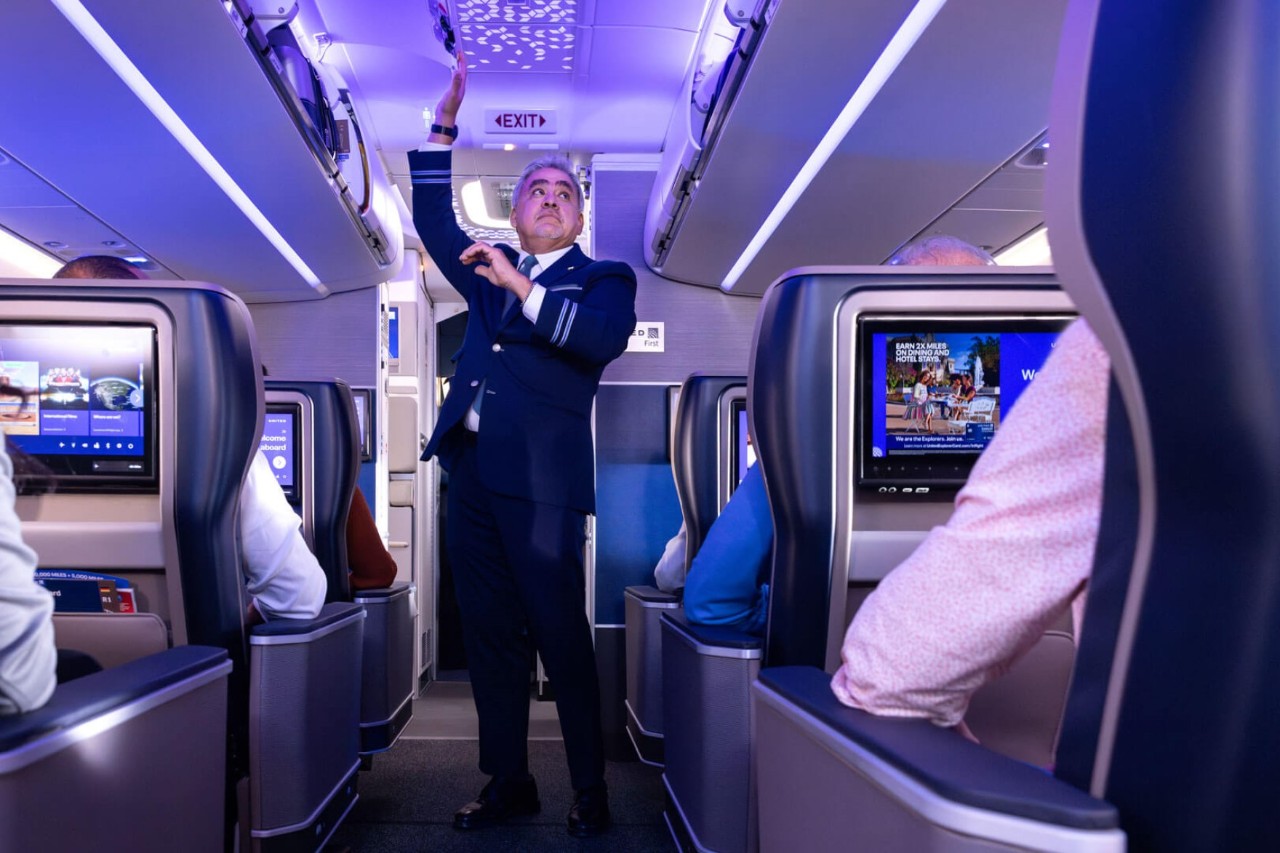 A crew member and passengers in a darkened aircraft cabin