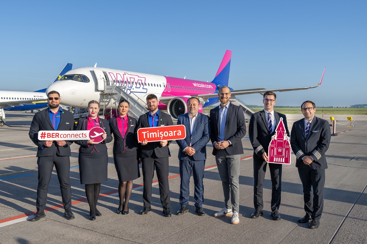 Eine Gruppe Menschen steht vor einem Flugzeug und hält Schilder in die Höhe / A group of people are standing in front of an aeroplane, holding up signs