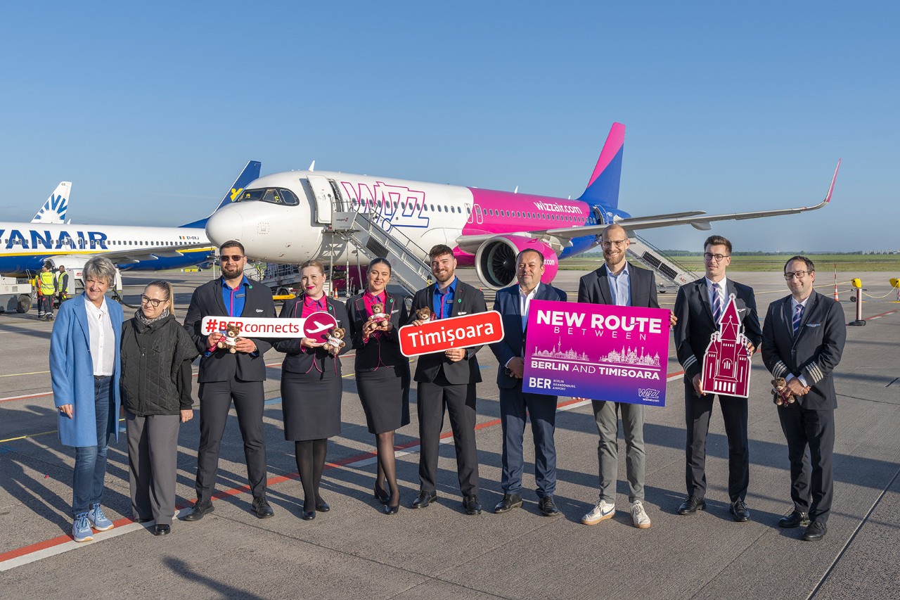 Eine Gruppe Menschen steht vor einem Flugzeug und hält Schilder in die Höhe / A group of people are standing in front of an aeroplane, holding up signs