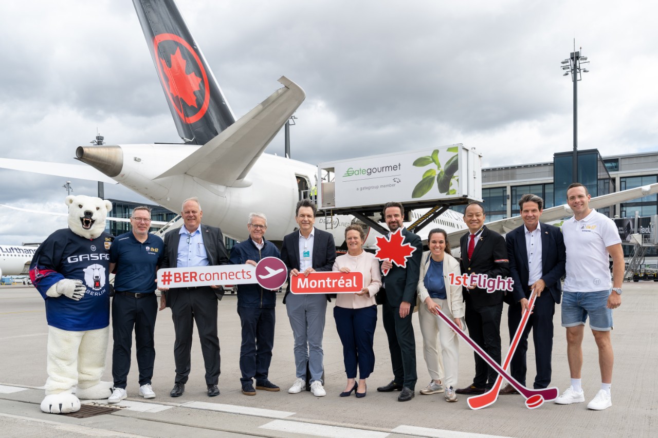 A group of people is standing in front of an Air Canada plane, holding signs and posing for a photo.