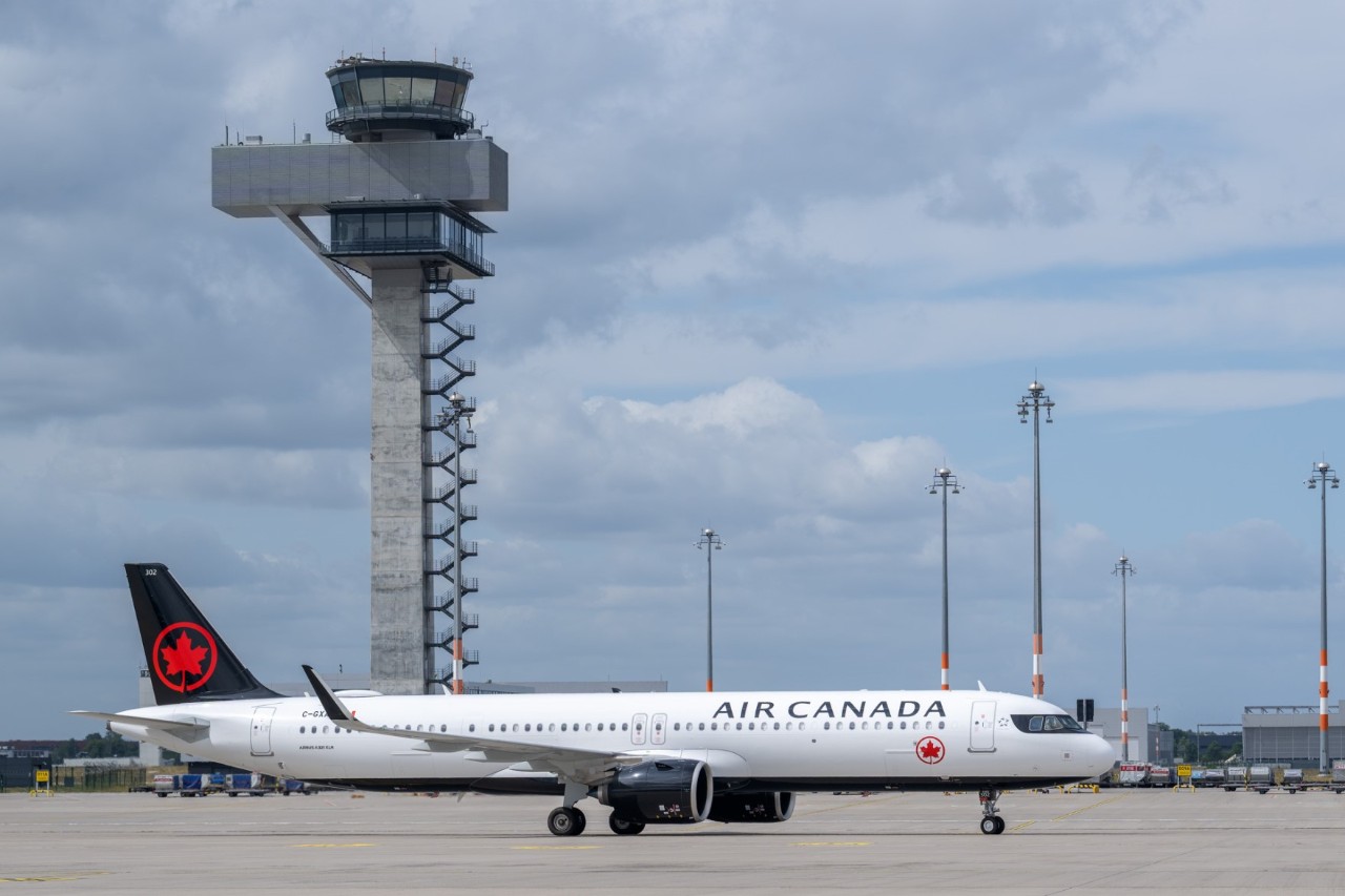 An Air Canada aircraft on the apron, with the control tower behind it.